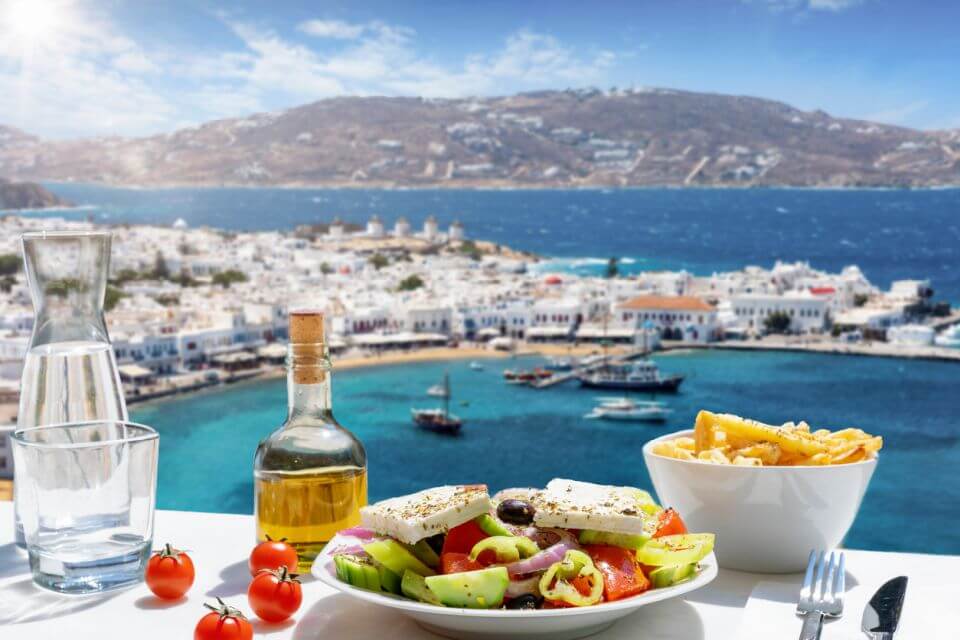 gastronomie Řecko Řecké jídlo se salátem, sýrem feta a olivovým olejem podávané s výhledem na ostrov Mykonos